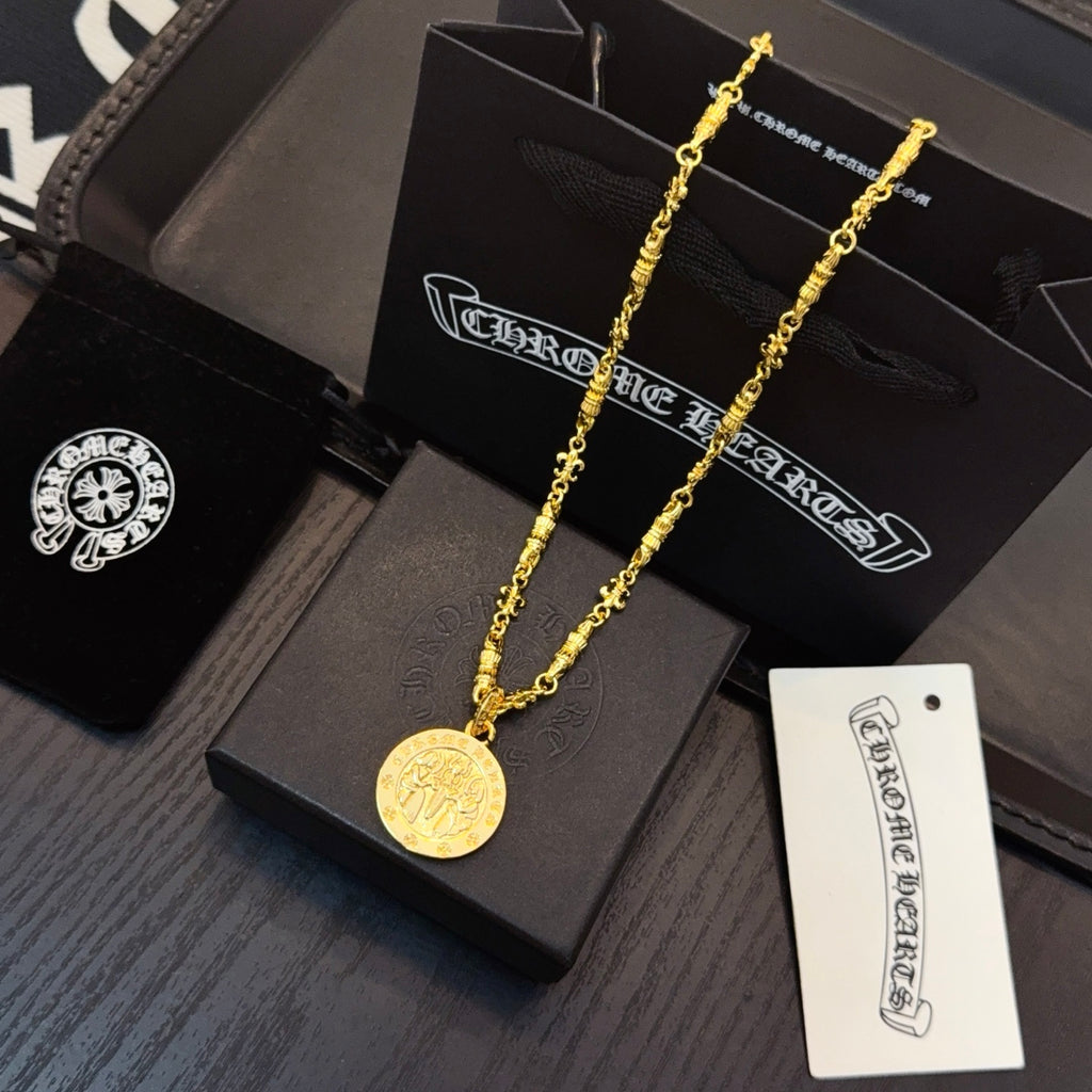 Gold-tone coin pendant necklace on black gift boxes with attached card