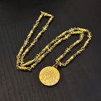 Gold-tone chain necklaces with round coin pendant on dark tabletop