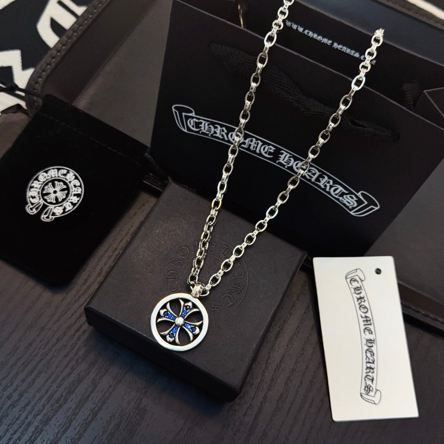 Round blue star pendant on layered silver-tone chain with jewelry tag