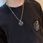 Round pendant necklace with blue star emblem on silver-tone chain worn