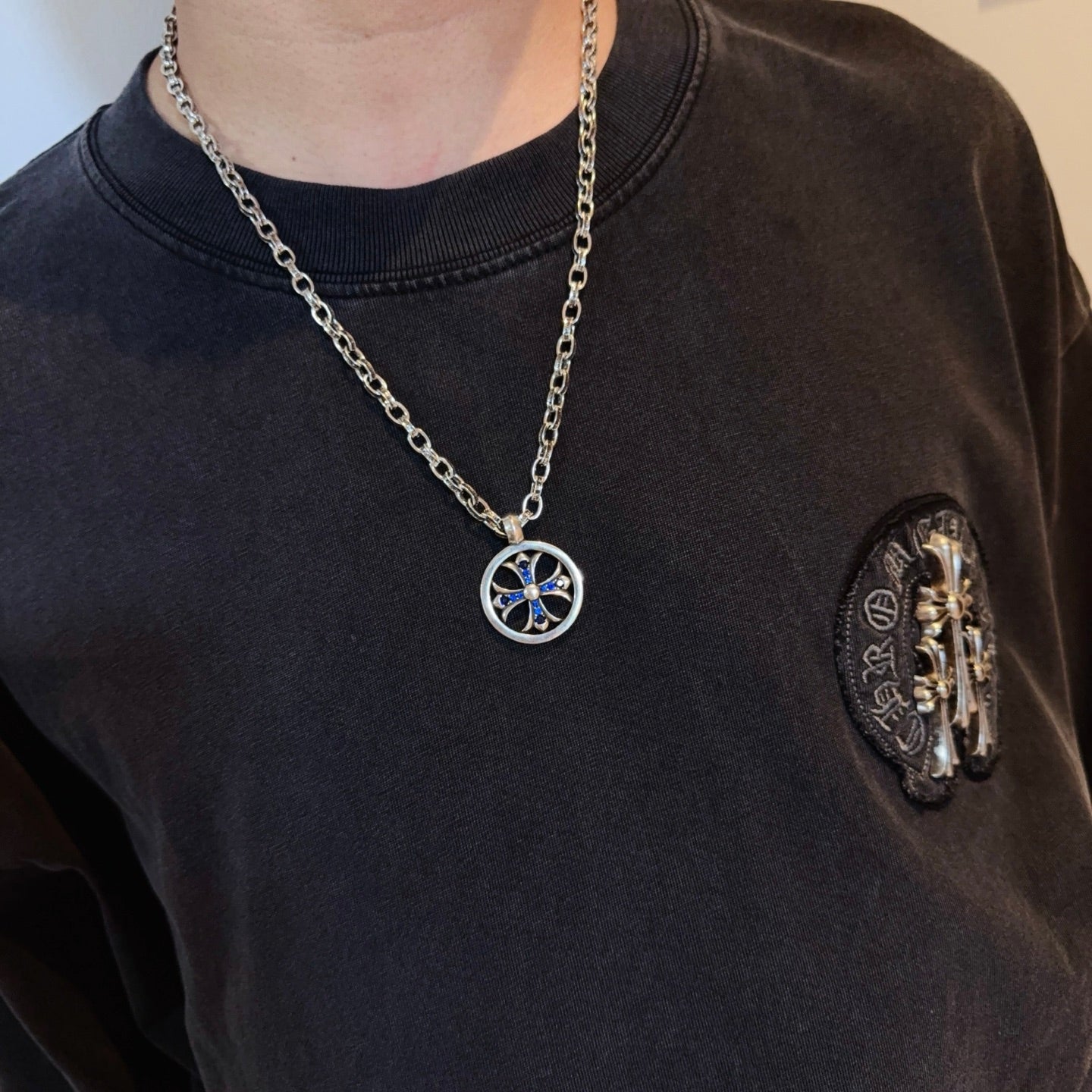 Round pendant necklace with blue star emblem on silver-tone chain worn