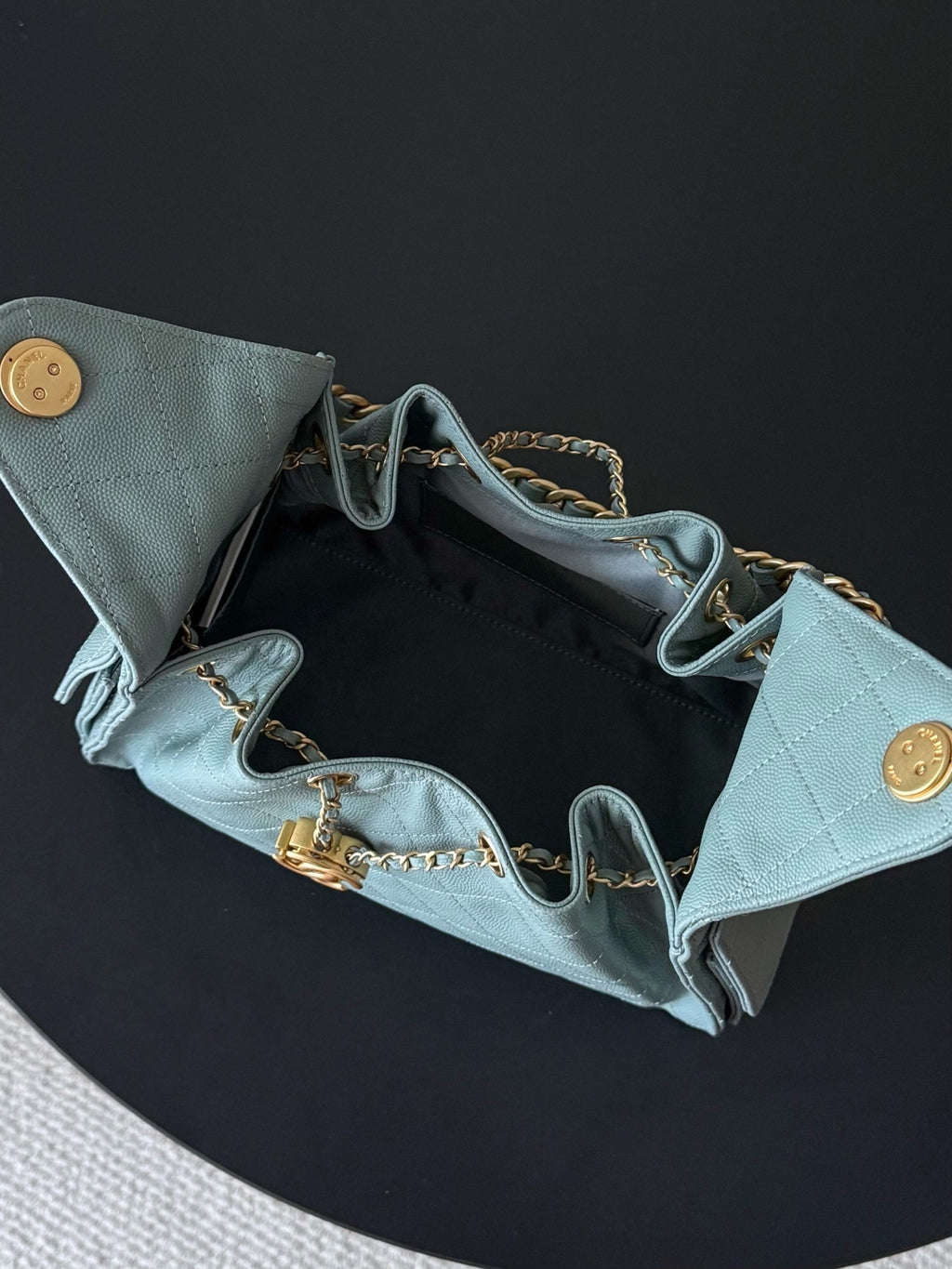 Chanel bag open interior showing light blue lining, chain straps, and gold hardware