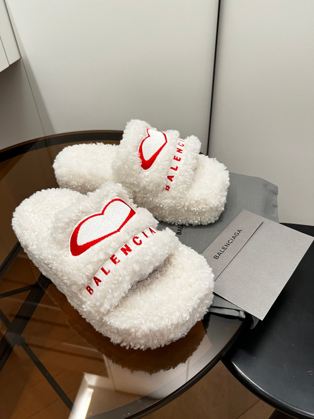 Sherpa slide sandals, white fuzzy straps with red logo; pair on gray boxes