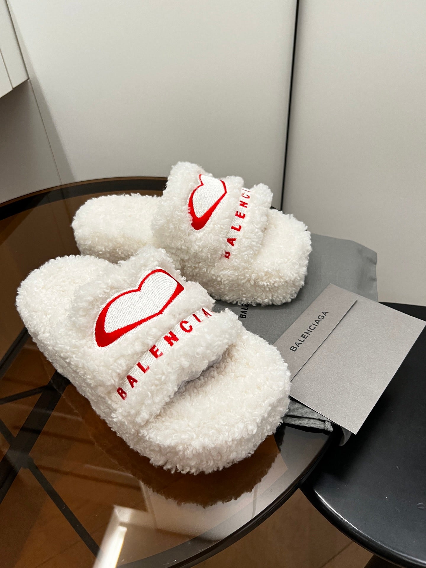 Sherpa slide sandals, white fuzzy straps with red logo; pair on gray boxes