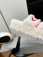 White sherpa slide sandal with red logo on fuzzy strap, side angle