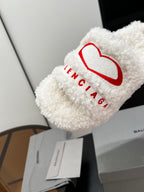White sherpa slide sandal with red logo and BALENCIAGA text on the strap