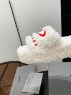 White sherpa slide sandal with red logo on fuzzy strap, side view