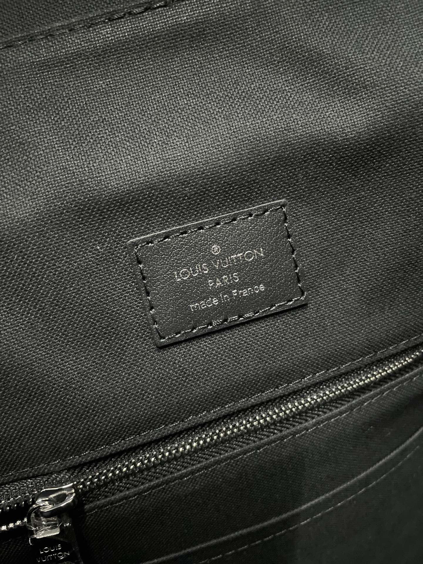 Louis Vuitton leather label on dark bag panel with stitched edge and zipper