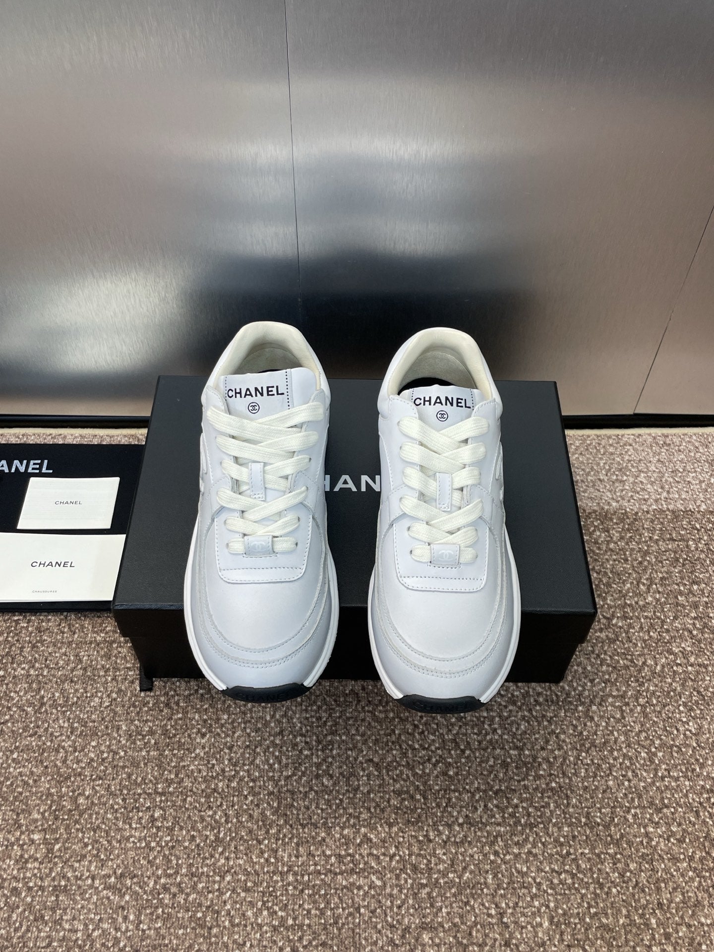 Chanel unisex white sneakers, front view pair on display boxes