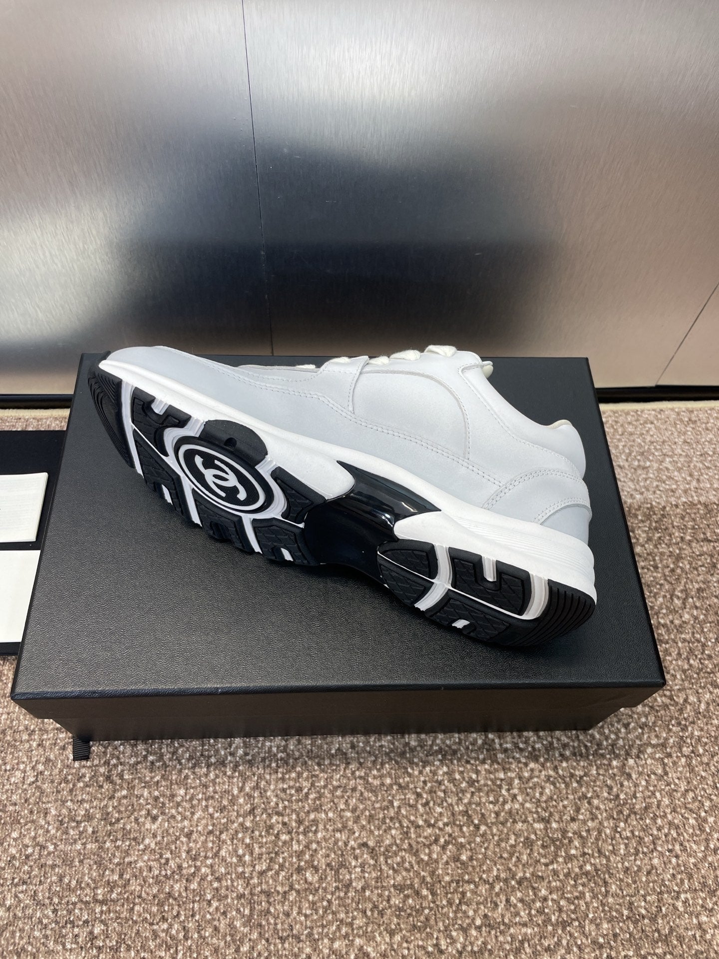Chanel unisex white sneakers, side view with black rubber outsole tread