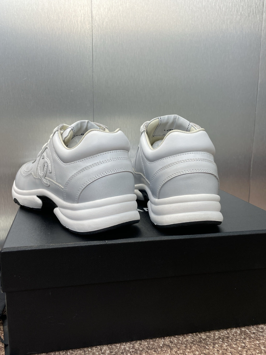 Chanel unisex white sneakers, heel back view pair on black box