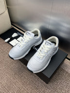 Chanel unisex white sneakers, three-quarter angle pair on black boxes