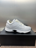 Chanel unisex white sneakers, side view on black box with logo detail