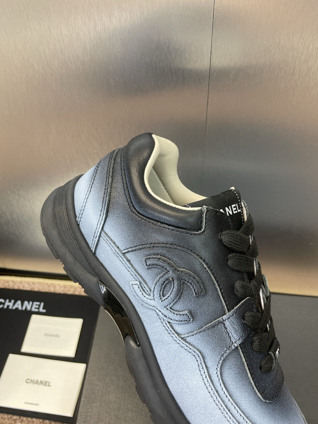 Unisex sneakers close-up, light blue leather with Chanel CC logo and black laces