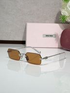 MiuMiu glasses with gold frame and brown tinted lenses, clear temple arms
