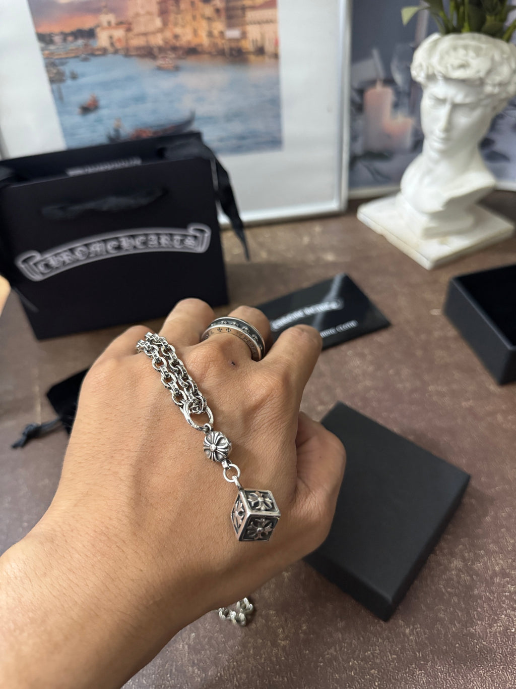 Chrome Hearts pendant necklace on hand with square cross charm and flower medallion