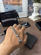 Chrome Hearts pendant necklace on hand with square cross charm and flower medallion