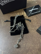 Silver-tone charm necklace with dangling square pendant over black drawstring pouch
