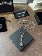 Silver-tone charm necklace with square pendant and small links on black box