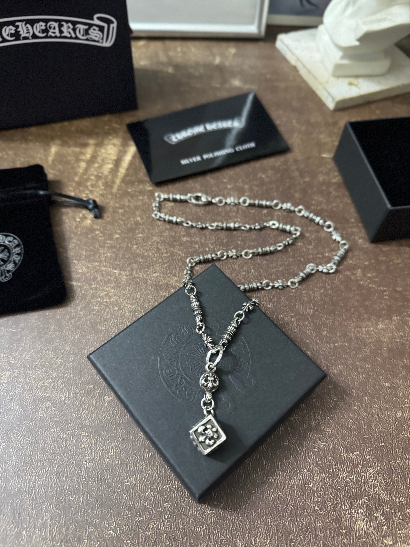 Silver-tone charm necklace with square pendant and small links on black box