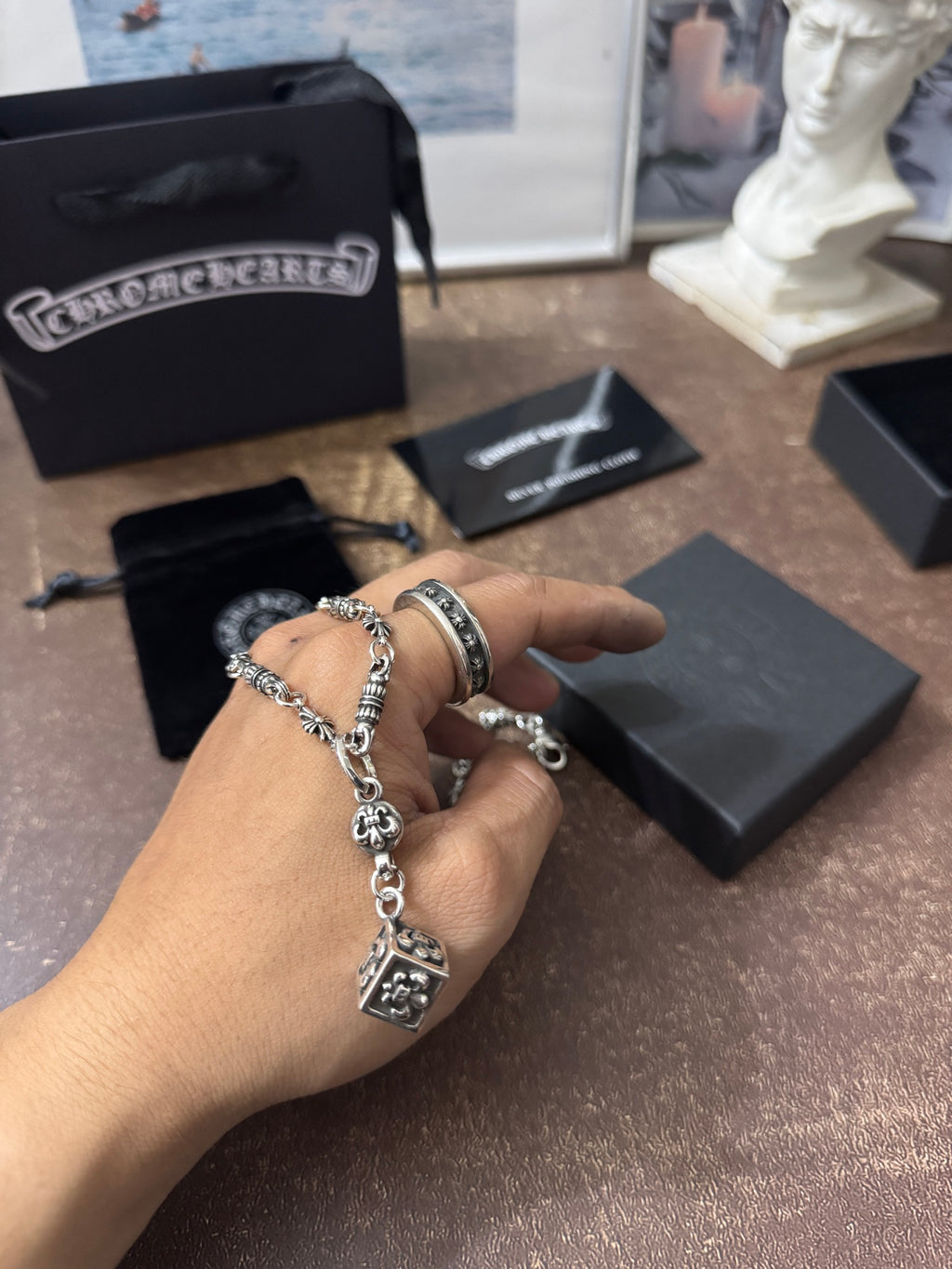 Silver-tone charm bracelet or necklace chain with square pendant held in hand