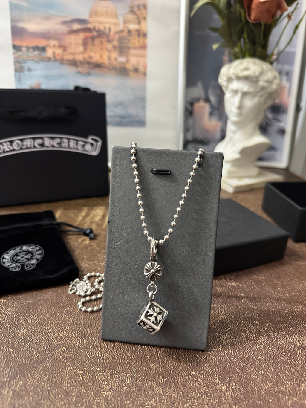 Silver-tone charm necklace on display card with round and square pendant charms.