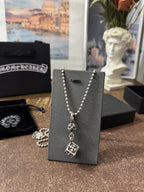 Silver-tone charm necklace on display card with round and square pendant charms.