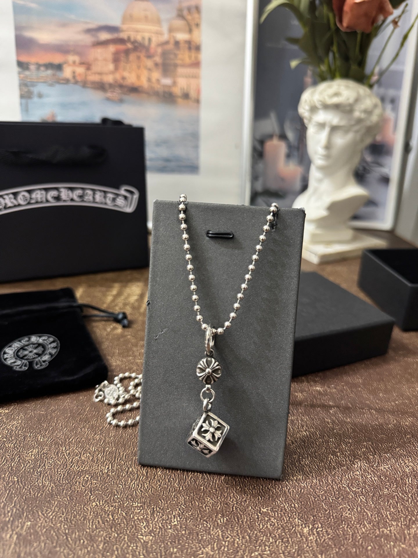 Silver-tone charm necklace on display card with round and square pendant charms.