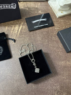 Silver-tone charm necklace with square pendant in black jewelry box, chain looped.