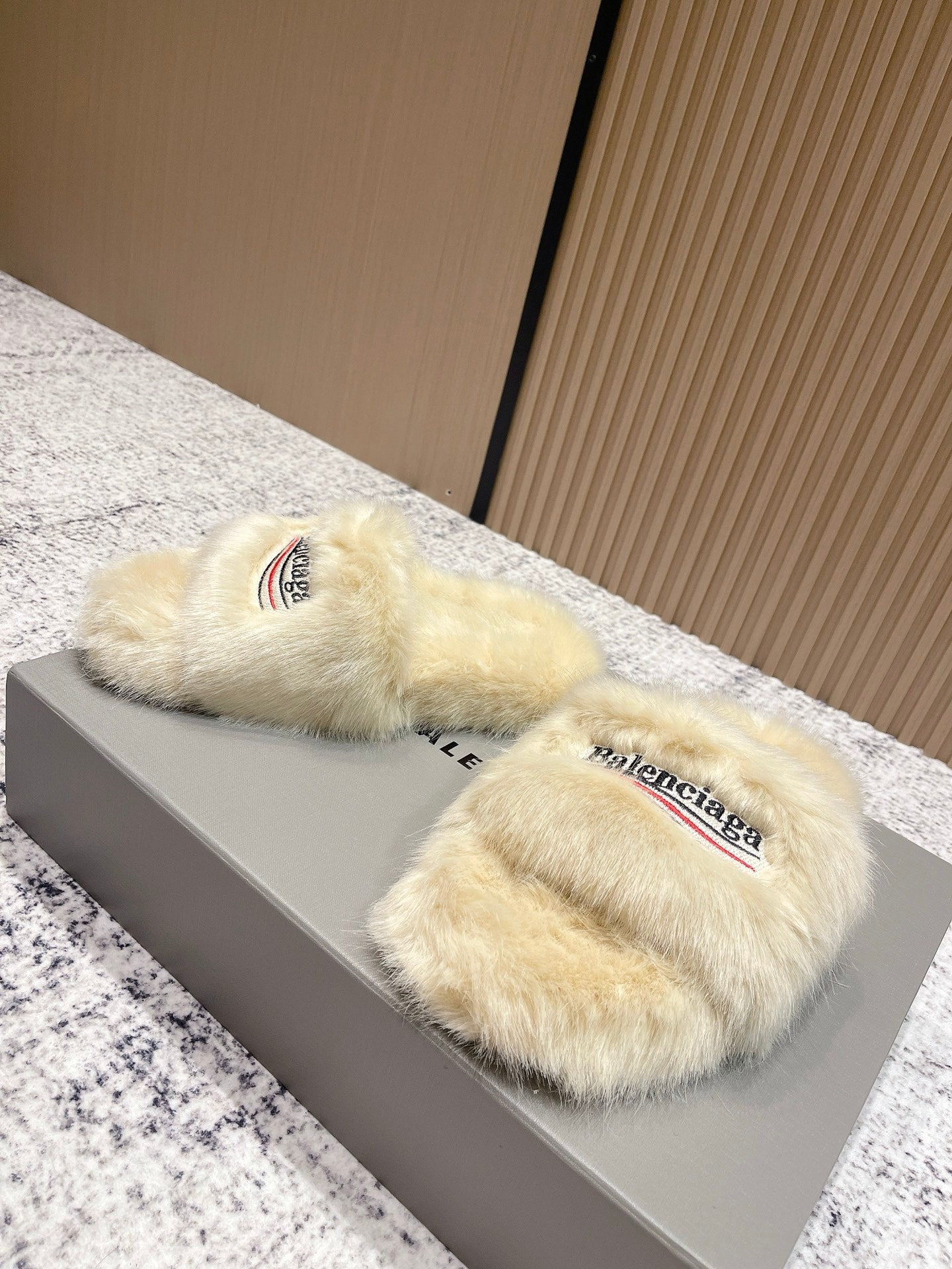 Faux fur slide sandals on box lid, cream straps with Balenciaga logo