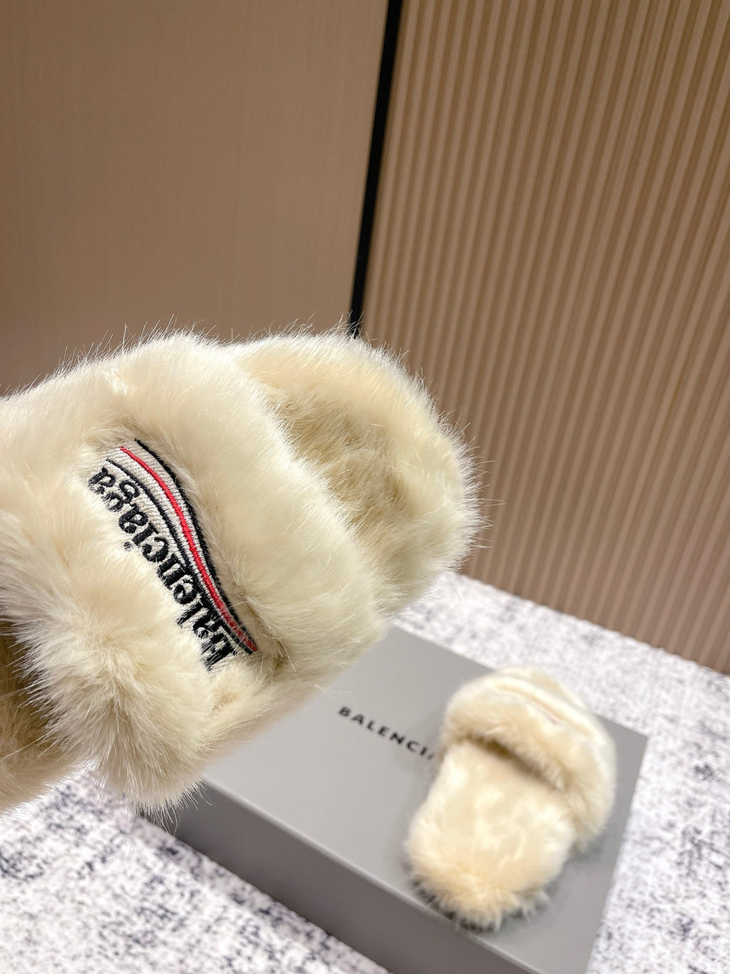 Close-up of cream faux fur slide sandal strap with Balenciaga logo