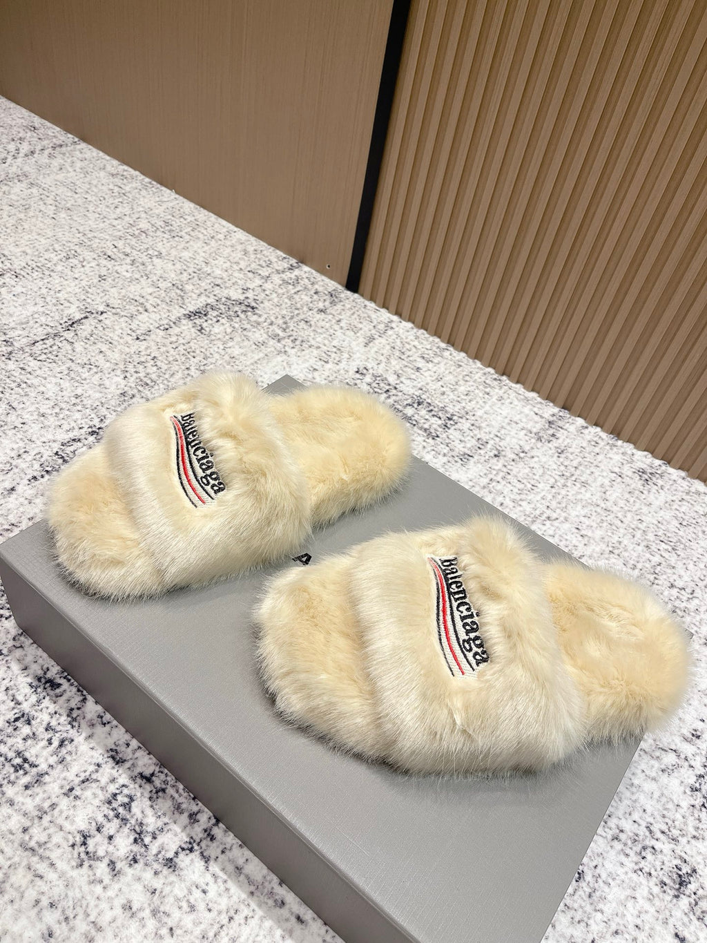 Pair of faux fur slide sandals with Balenciaga logo on cream straps