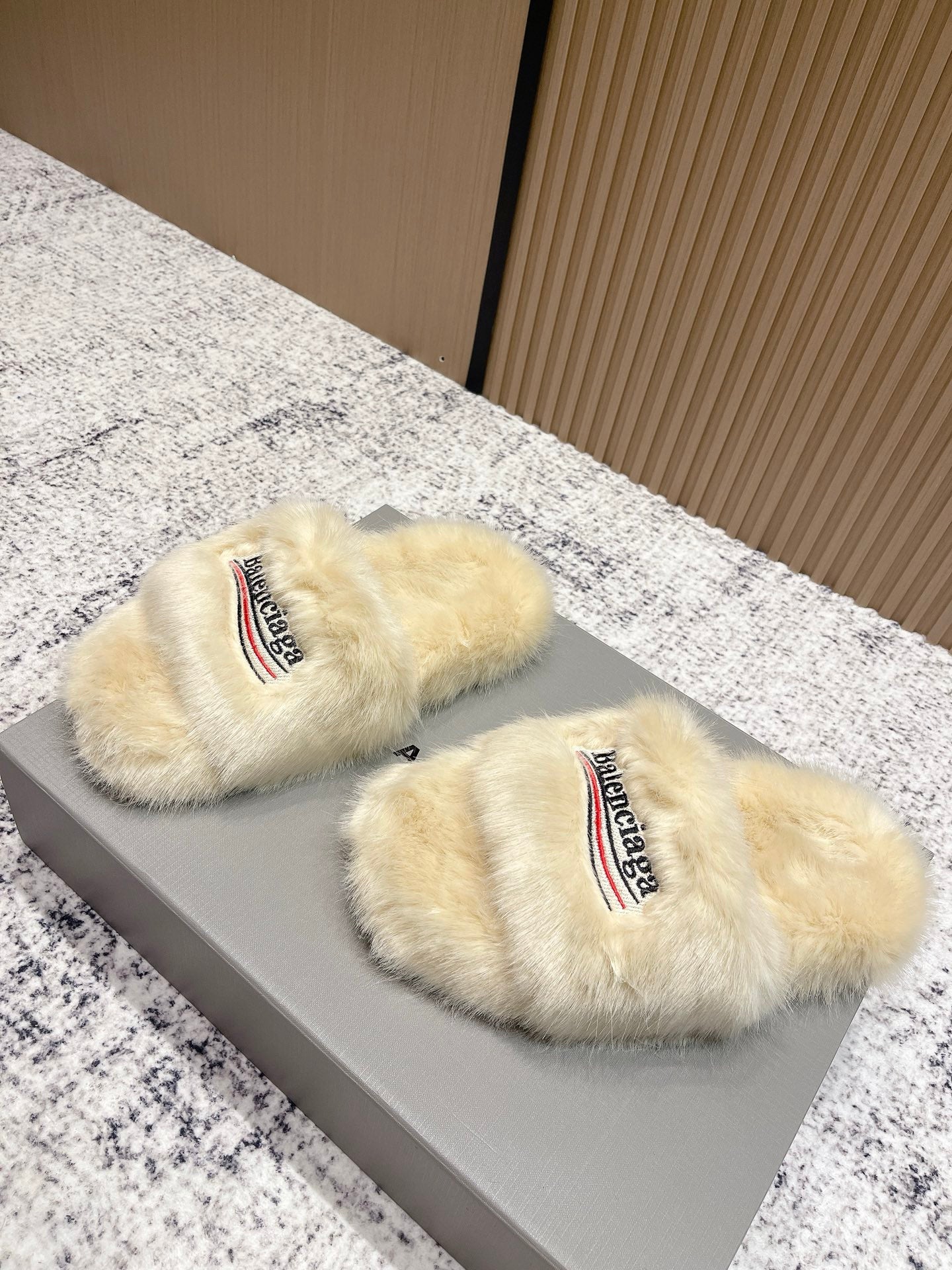 Pair of faux fur slide sandals with Balenciaga logo on cream straps