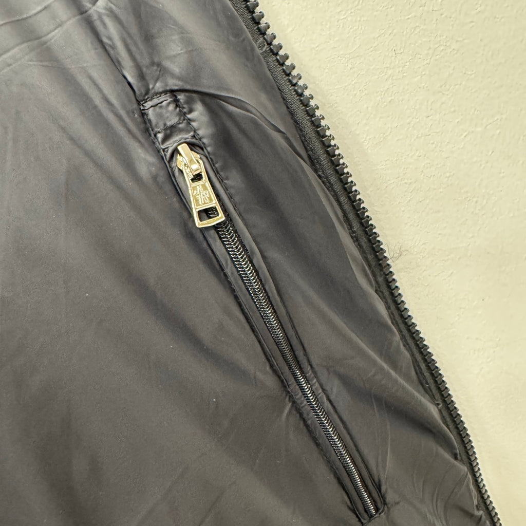 Puffer jacket zipper with metal pull and dark quilted fabric, close-up