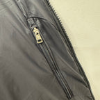 Puffer jacket zipper with metal pull and dark quilted fabric, close-up