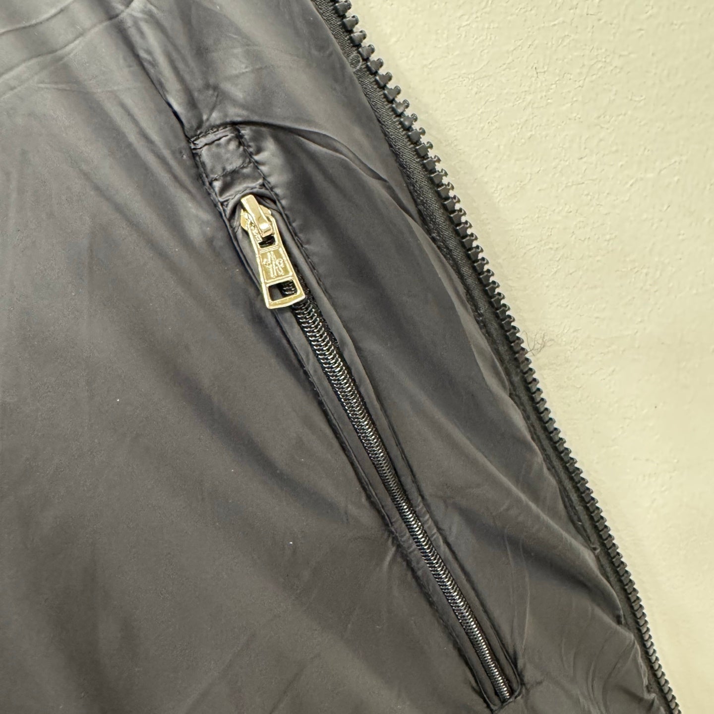 Puffer jacket zipper with metal pull and dark quilted fabric, close-up