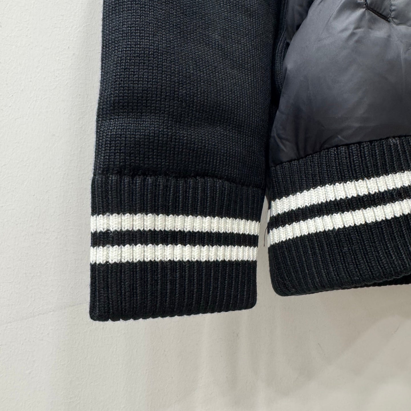 Ribbed knit sleeve cuff with white striped band on dark puffer jacket