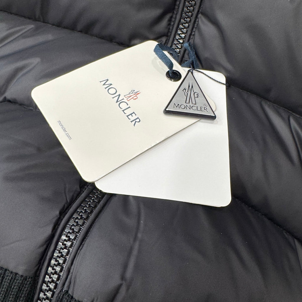 Moncler hang tags on dark puffer jacket lining with brand cards
