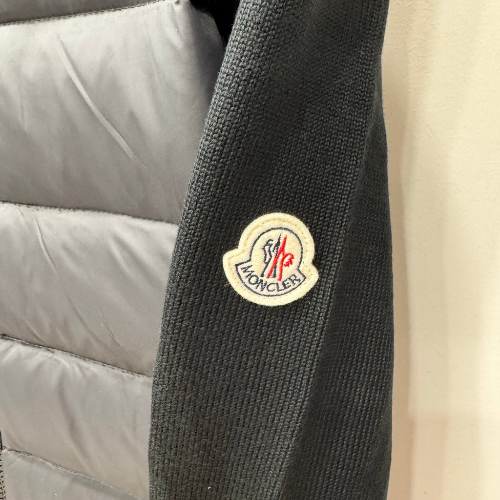 Moncler patch on ribbed knit cuff of dark puffer jacket, striped trim