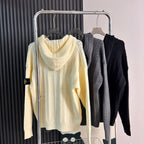 Cable-knit zip hoodies on rack: cream, gray, and dark styles