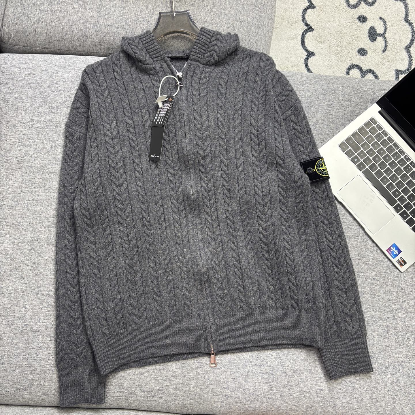 Gray cable-knit zip hoodie with hood, ribbed cuffs and hem on couch