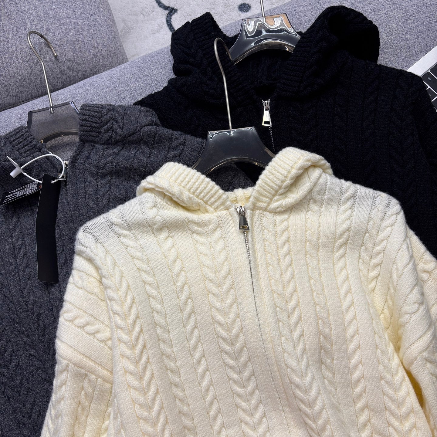Cream cable-knit zip hoodie with hood and zipper, close-up on hanger