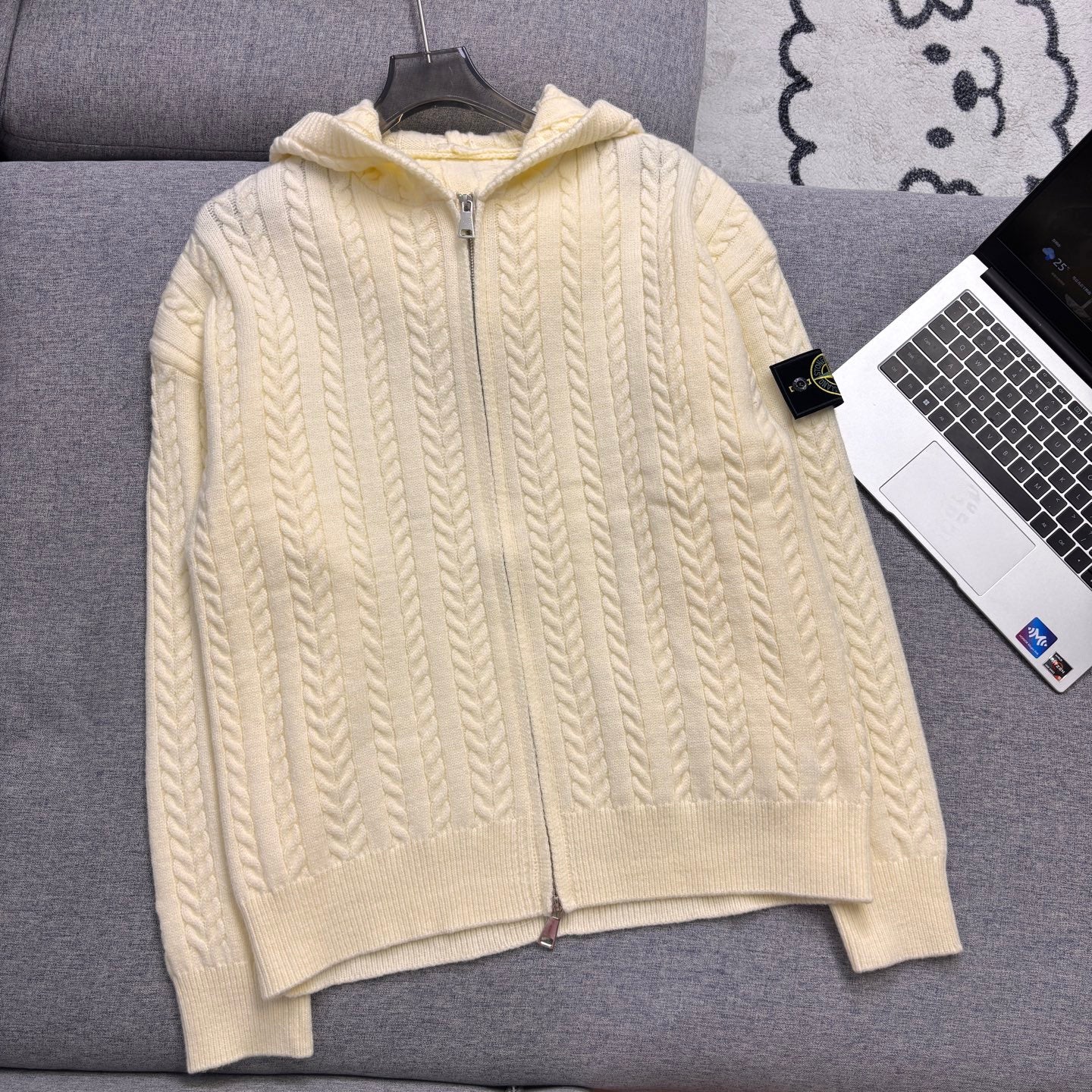 Cream cable-knit zip hoodie with hood, ribbed cuffs and hem on couch