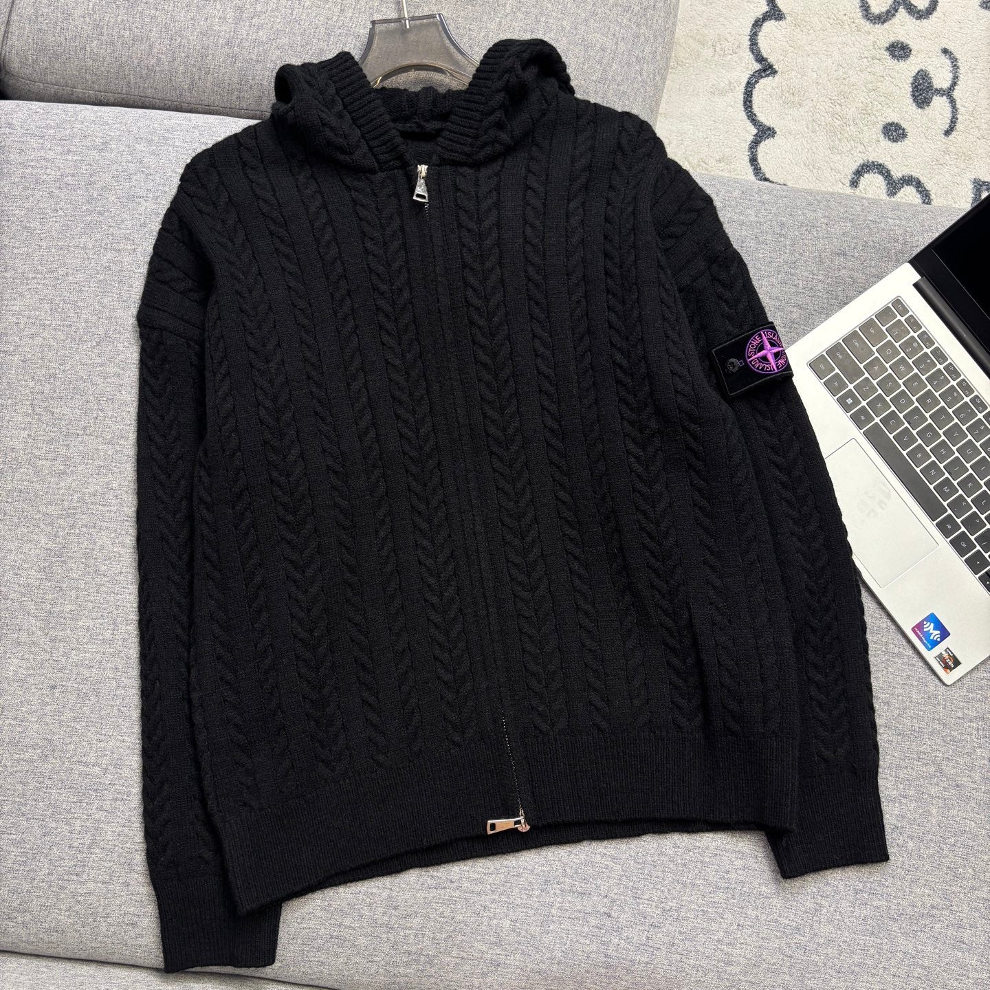 Black cable-knit zip hoodie with hood, ribbed cuffs and hem on couch