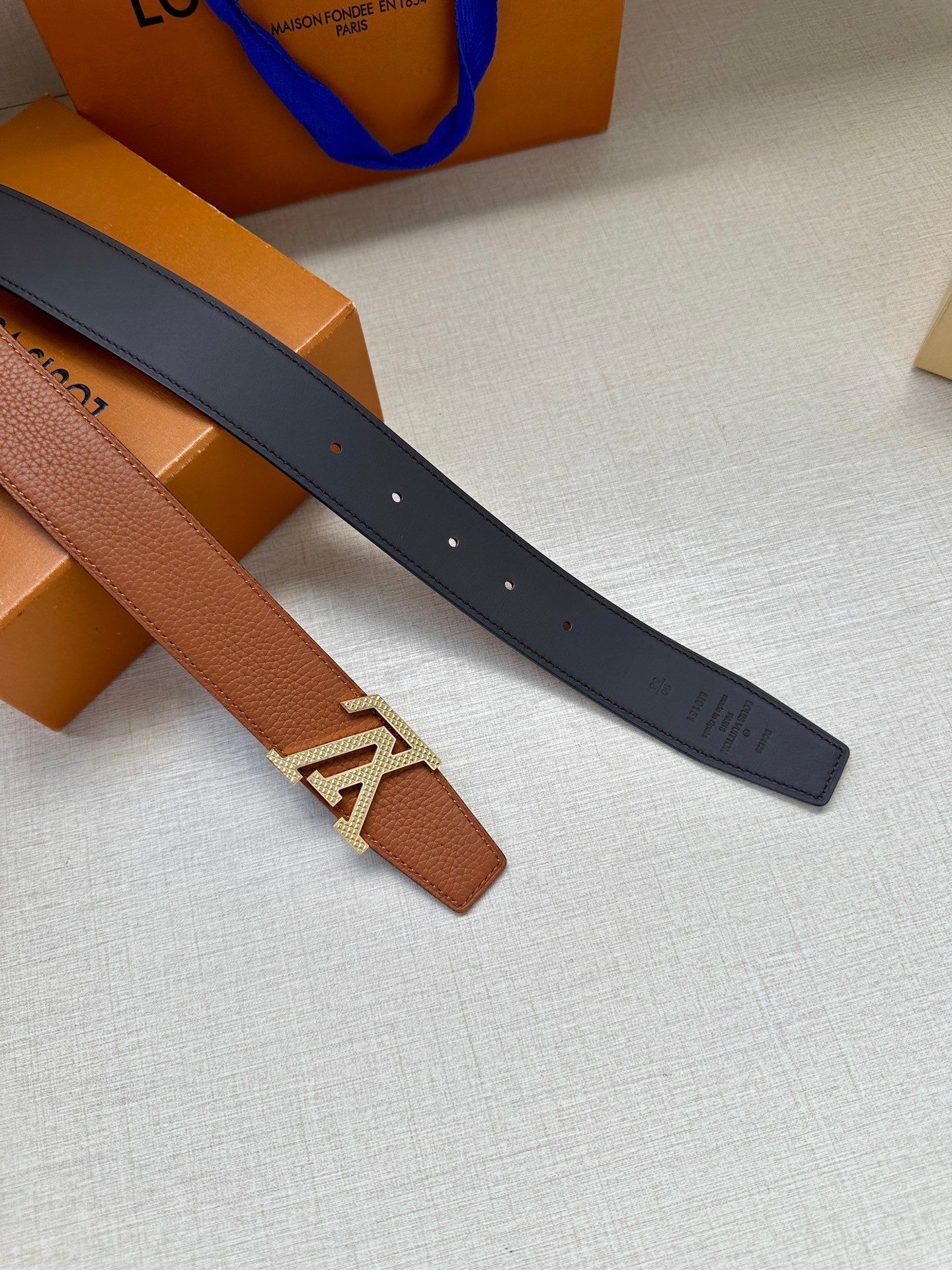 Louis Vuitton belt pair view: tan strap with LV buckle and dark strap with holes