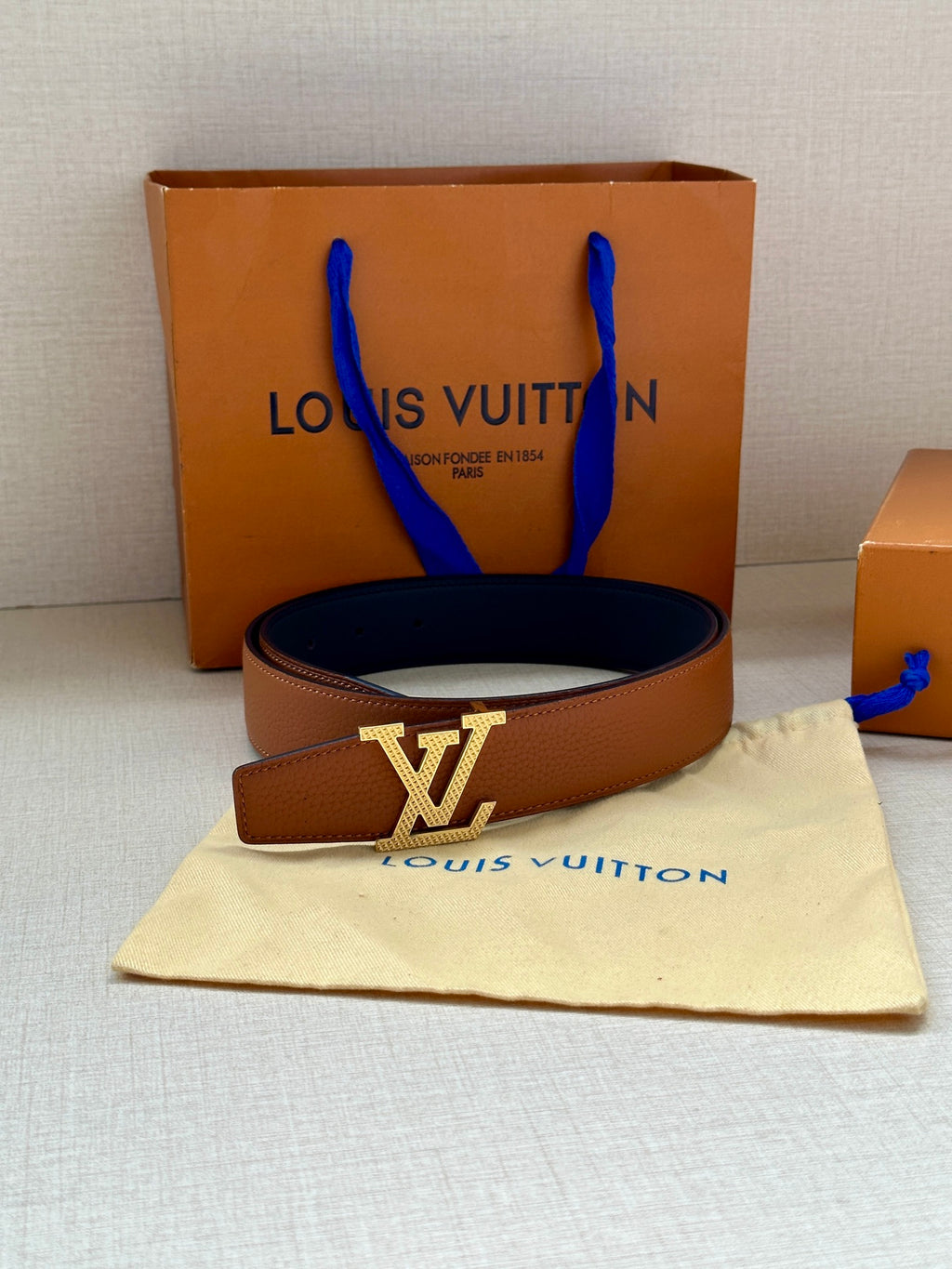 Louis Vuitton tan leather belt with large LV buckle and blue-stem pouch bag