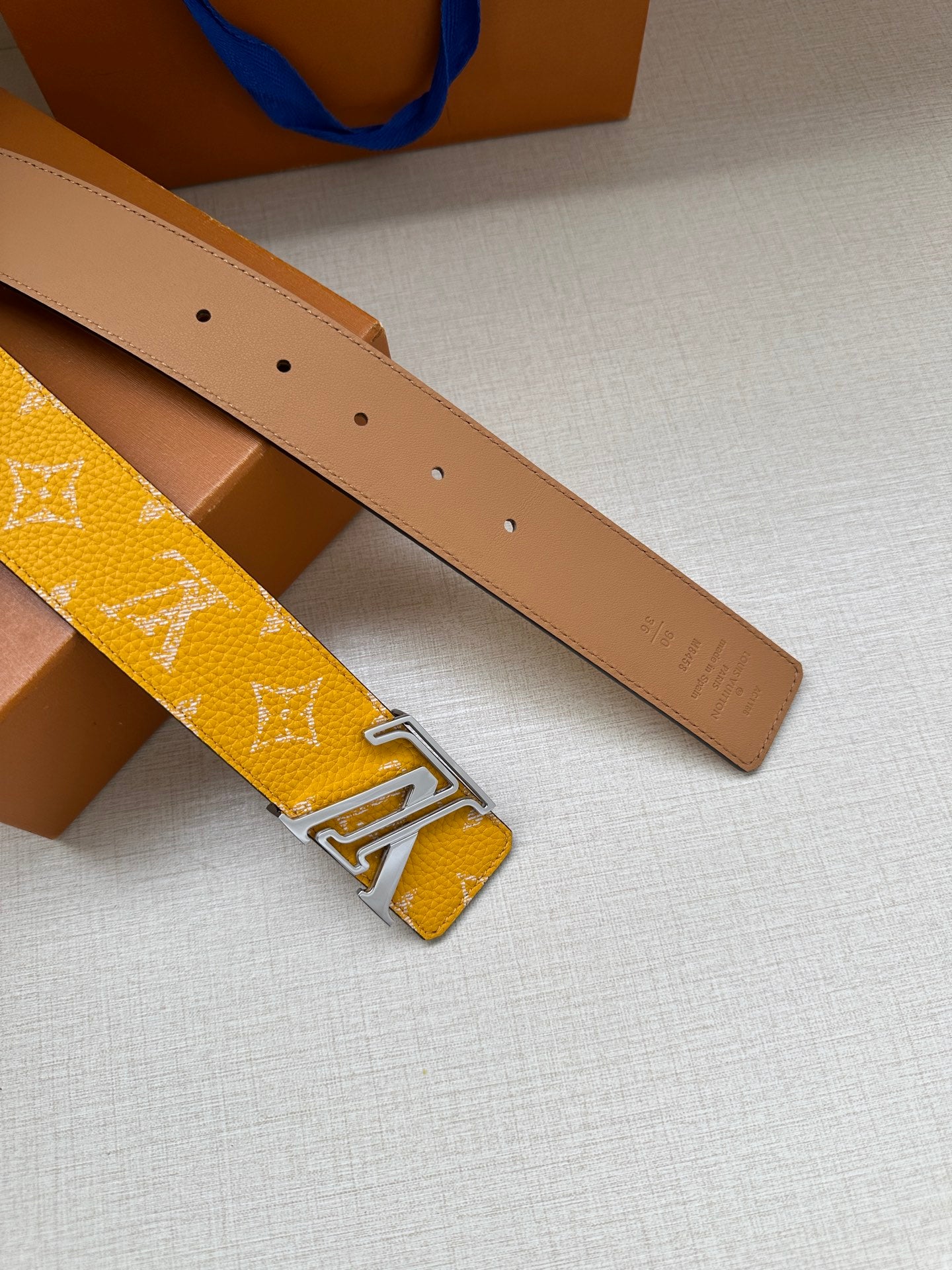 Yellow monogram belt and tan leather belt with punched holes