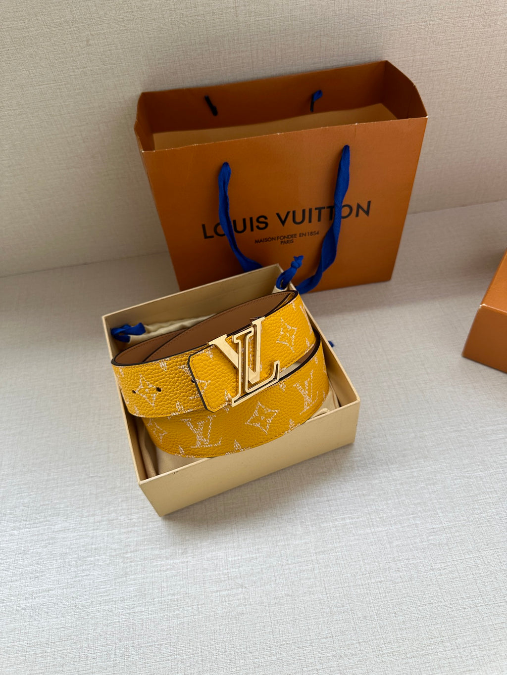 Yellow monogram belt with gold-tone LV buckle on display stand