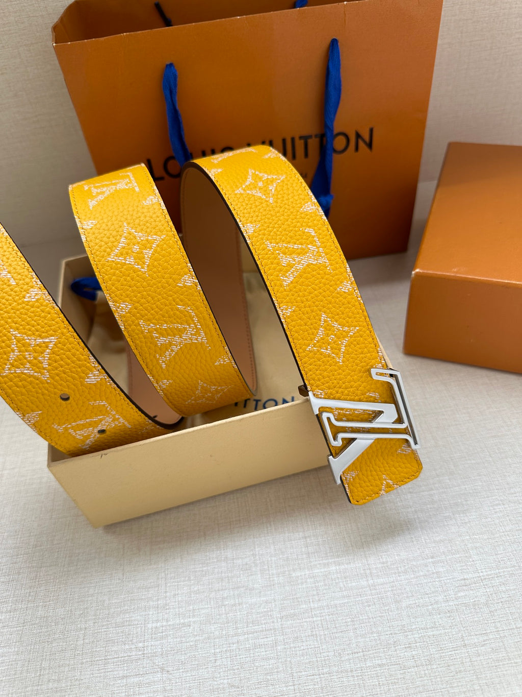 Yellow monogram belt buckle close-up with adjustable strap end