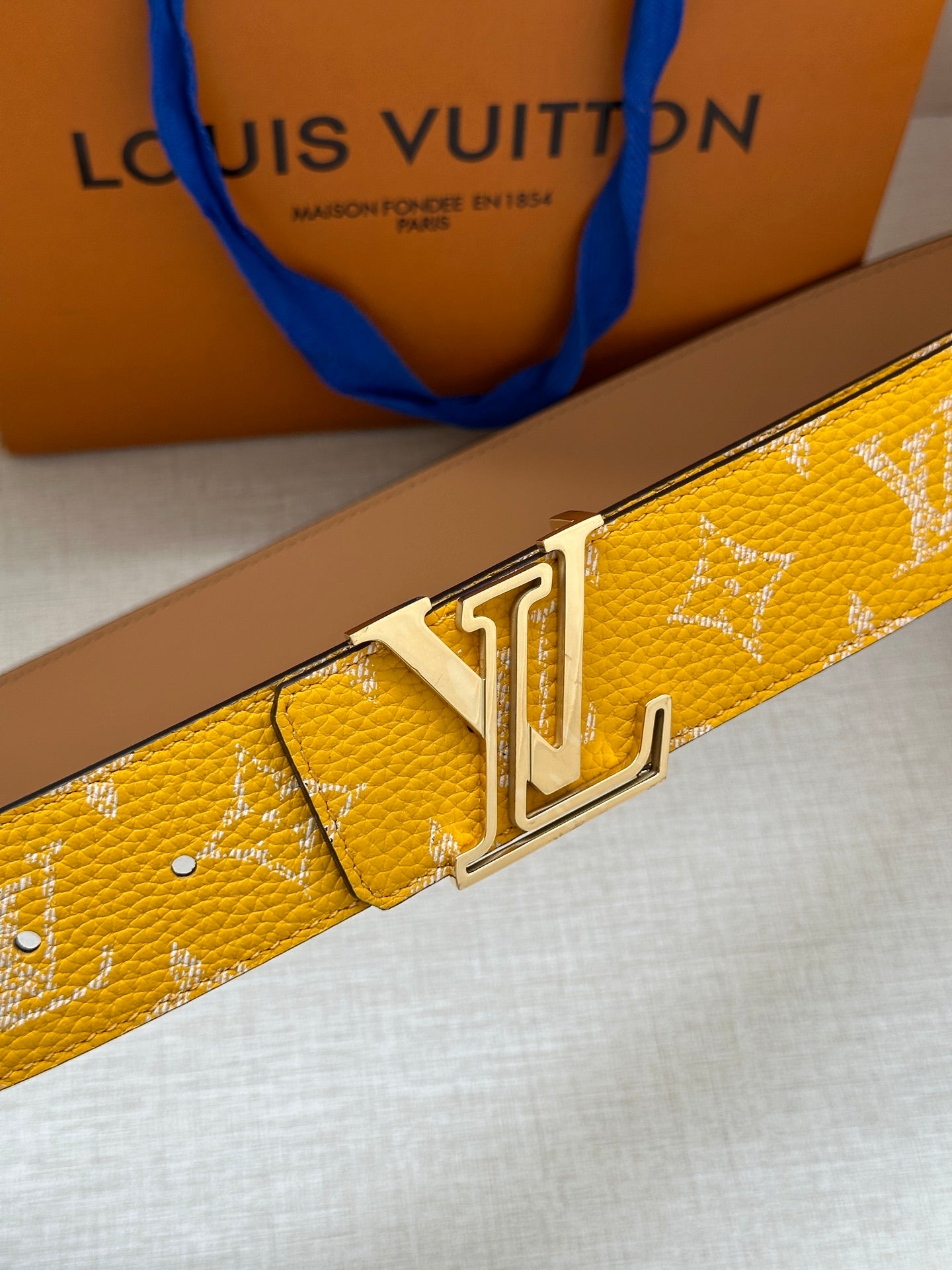 Yellow monogram belt, close-up of gold-tone buckle and keeper